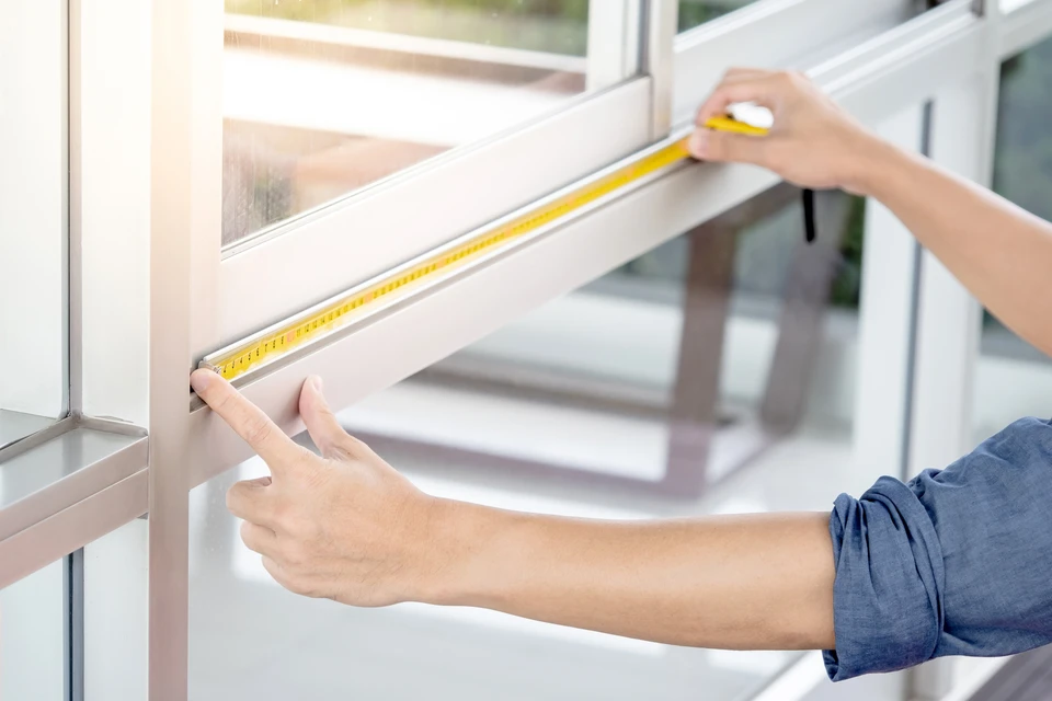Mâles de travailleurs masculins utilisant la dimension de contrôle des mesures sur le cadre de fenêtre en aluminium sur le chantier de construction