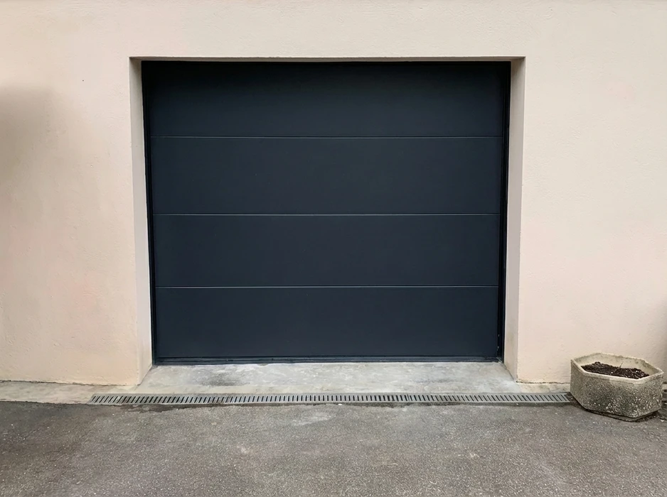 Porte de garage sectionnelle motorisée, finition lisse, coloris gris anthracite (RAL 7016), montée en applique dans une ouverture maçonnée