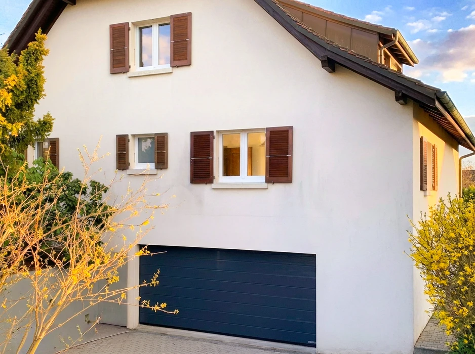 Façade extérieure d'une maison individuelle de style européen, crépi blanc, volets en bois brun foncé, fenêtres PVC blanches double vantaux