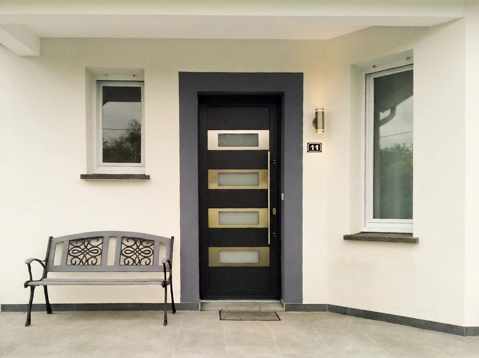 Entrée extérieure d'une maison individuelle avec une porte d'entrée moderne anthracite à simple vantail, équipée de cinq fenêtres carrées en verre dépoli disposées verticalement avec inserts horizontaux en aluminium brossé